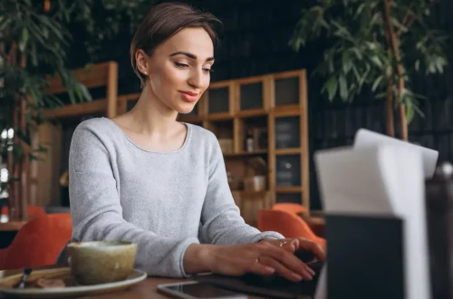 Woman sitting on a cafe using her computer to access the fast it platform