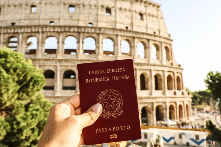 Photo of a person showing their Italian passport in front of the Colosseum