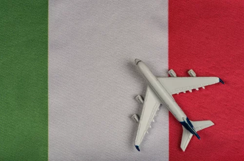 When did italians immigrate: Photo of a model plane on top of the Italian flag