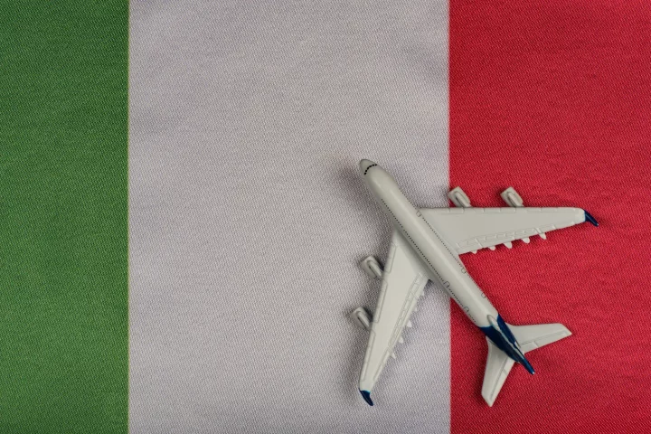 When did italians immigrate: Photo of a model plane on top of the Italian flag