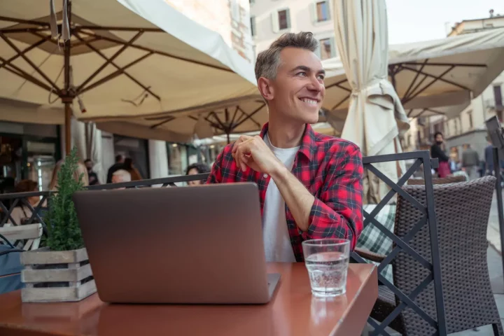 Working in Italy as an American citizen: Photo of a man remote working in a street cafe in Rome